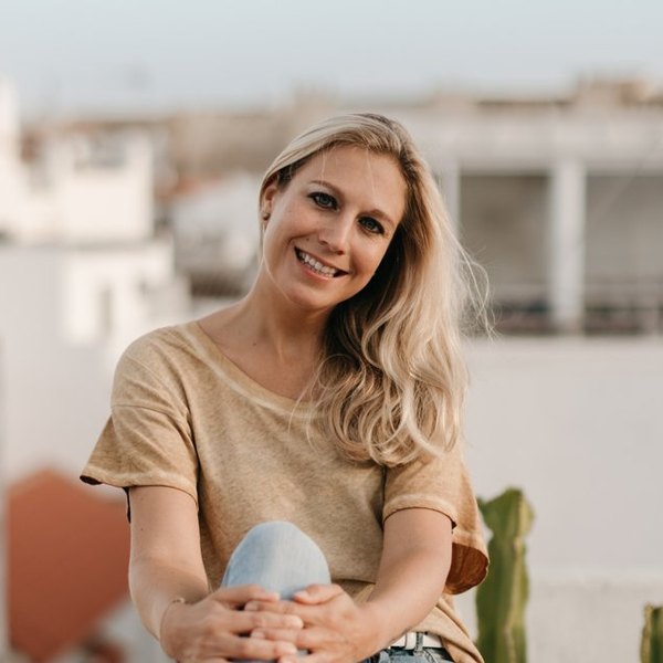 Sina Heider sitzt lachend auf einer Dachterrasse